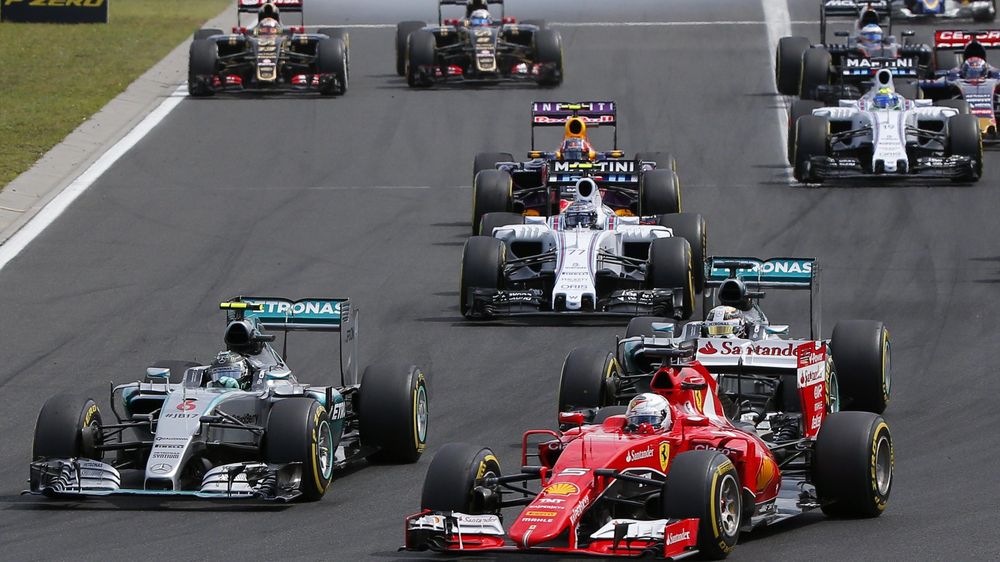 Ferrari Formula One driver Sebastian Vettel of Germany (R) overtakes Mercedes Formula One driver Nico Rosberg of Germany (L) and Mercedes Formula One driver Lewis Hamilton of Britain after the start of the Hungarian F1 Grand Prix at the Hungaroring circui