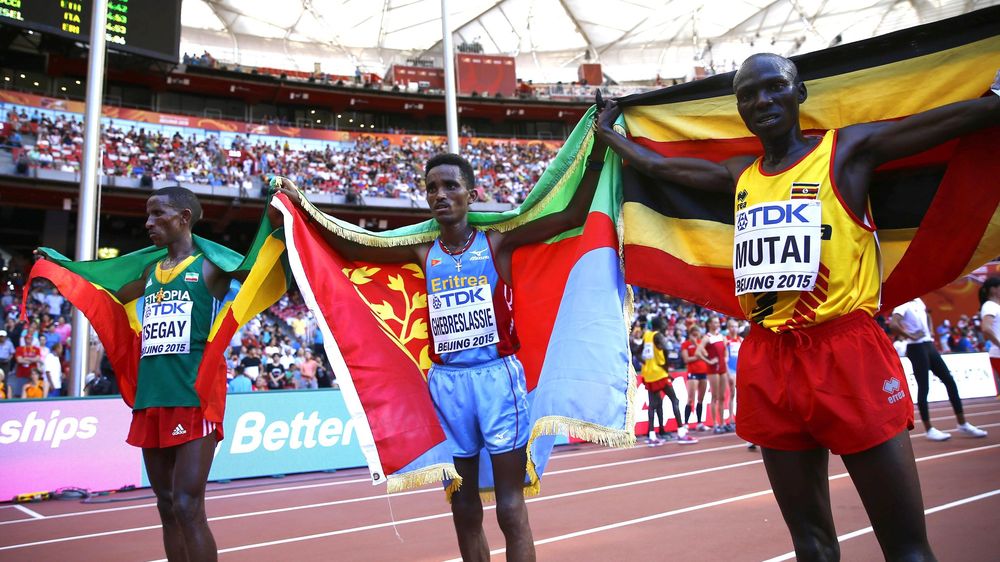Winner Ghirmay Ghebreslassie of Eritrea (C), second placed Yemane Tsegay of Ethiopia (L) and third placed Munyo Solomon Mutai of Uganda celebrate with their national flags after crossing the finish line in the men's marathon.
