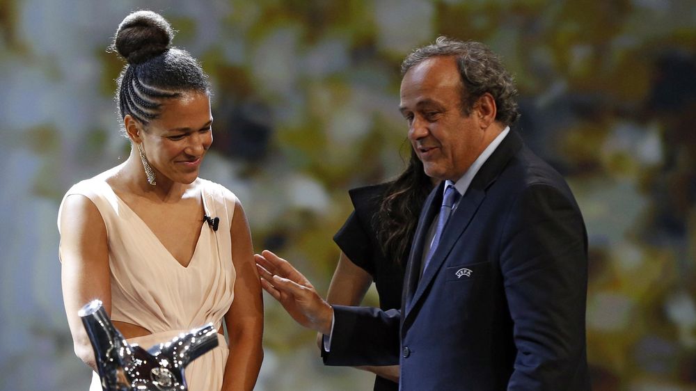 UEFA president Michel Platini (R) hands over to Germany's Celia Sasic the trophy of Best Women's player in Europe at the end of the UEFA Champions League Group stage draw ceremony, on August 27, 2015 in Monaco
