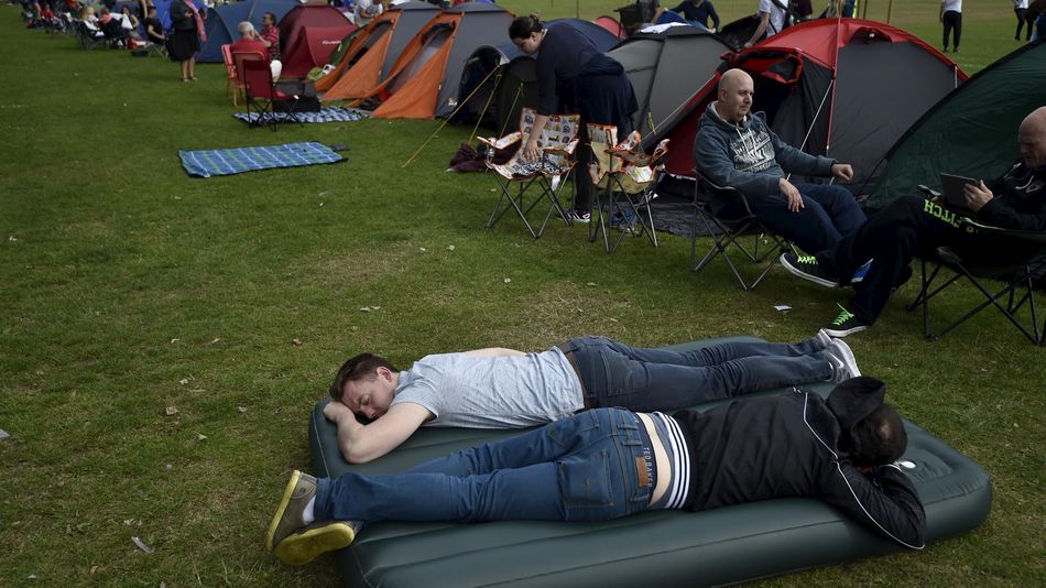 Tennis fans relax after setting up their tents in the ticket queue at Wimbledon