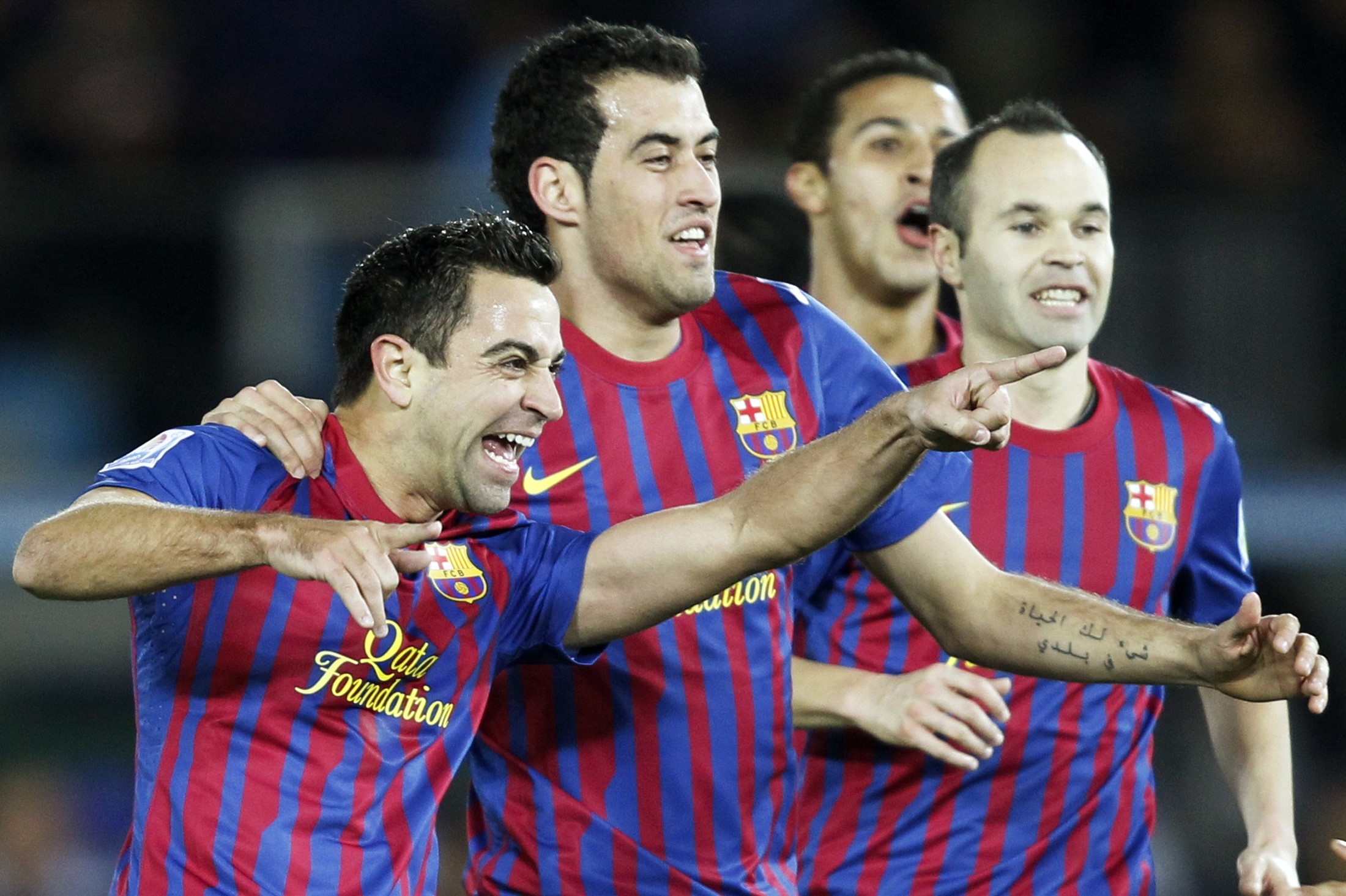 Xavi (L) of Spain's Barcelona celebrates a goal against Brazil's Santos with his teammates Sergio Busquets (2nd L), and Andres Iniesta