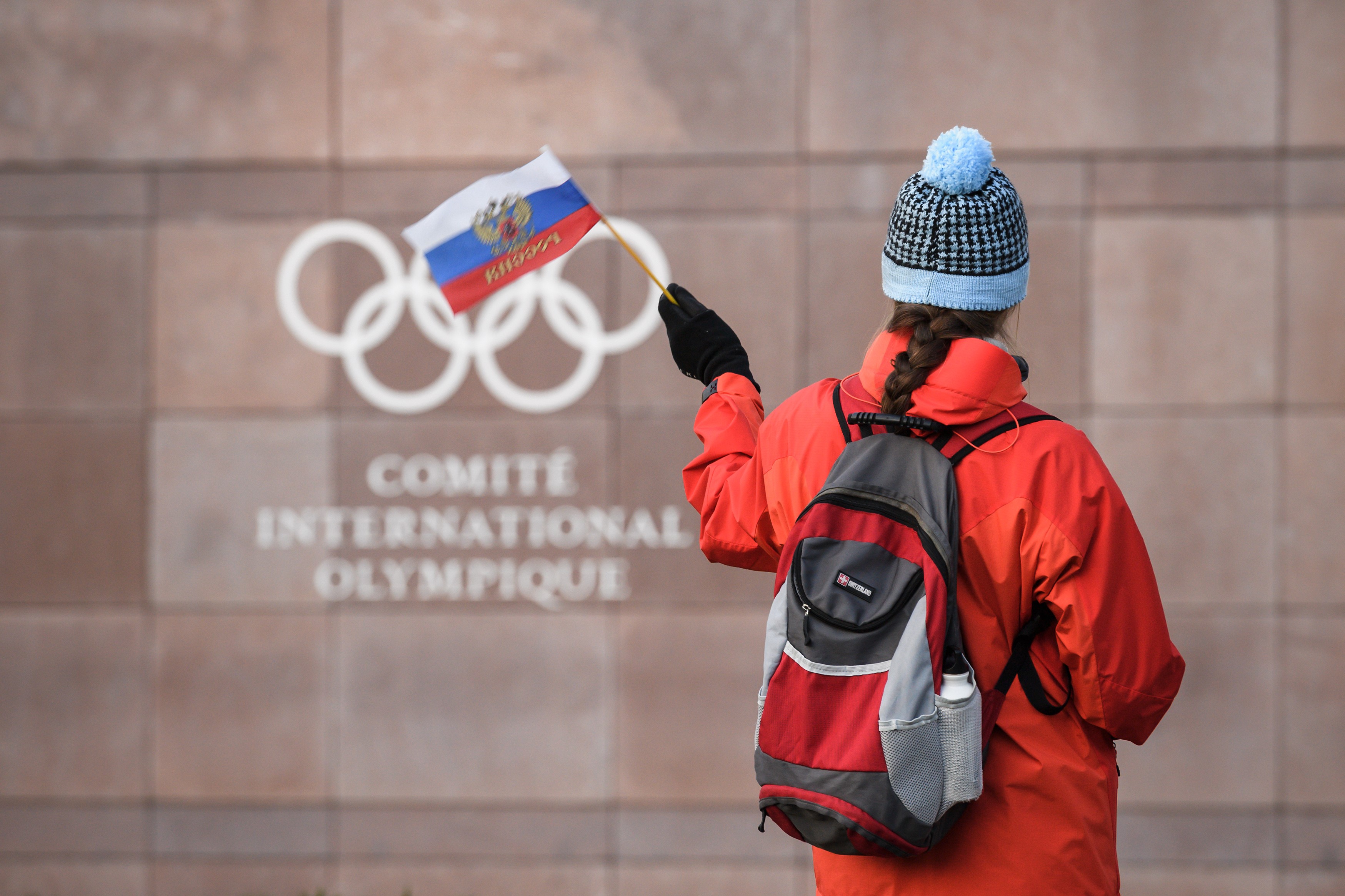 A supporter waves a Russian flag in front of the logo of the International Olympic Committee (IOC) at their headquarters on December 5, 2017 in Pully near Lausanne. The International Olympic Committee opened a high-stakes summit on December 5 on whether t