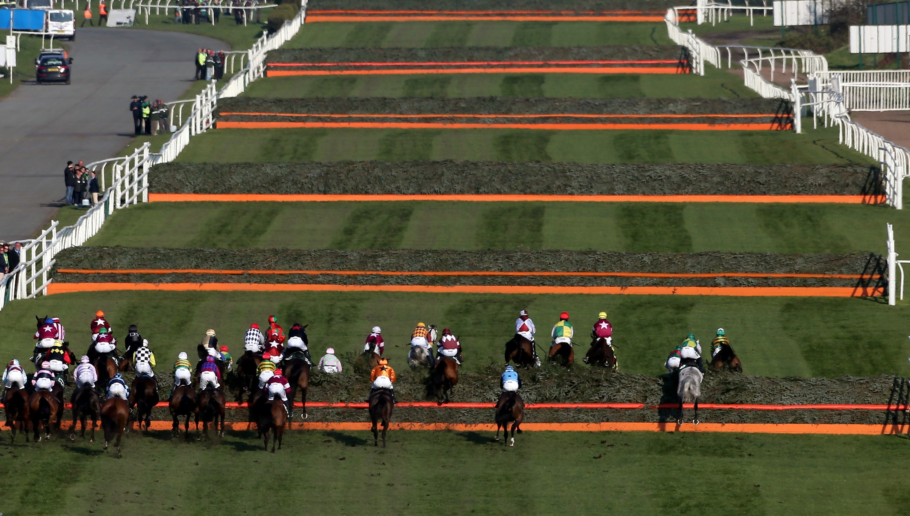 Grand National’ın start düzlüğünde atlar peş peşe altı engel geçiyor. (Bu görsel The Jockey Club'ın izniyle kullanılmıştır)