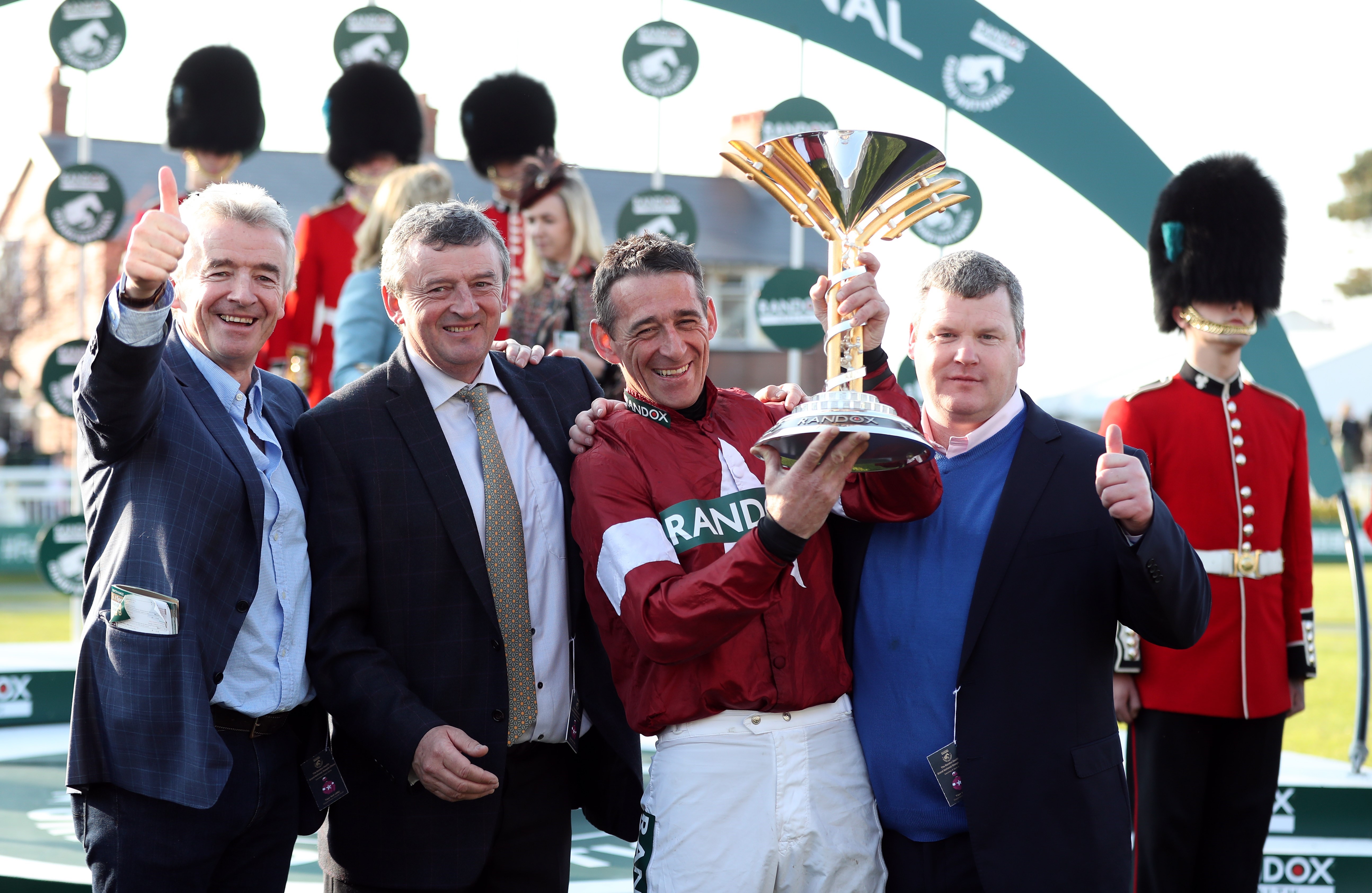 Şampiyonlar kupalarıyla: At sahibi Michael O’Leary, jokey Davy Russell ve antrenör George Elliott. (Bu görsel The Jockey Club'ın izniyle kullanılmıştır)