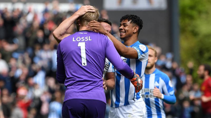 Huddersfield Town's Danish goalkeeper Jonas Lossl (L) is congratulated by teammates