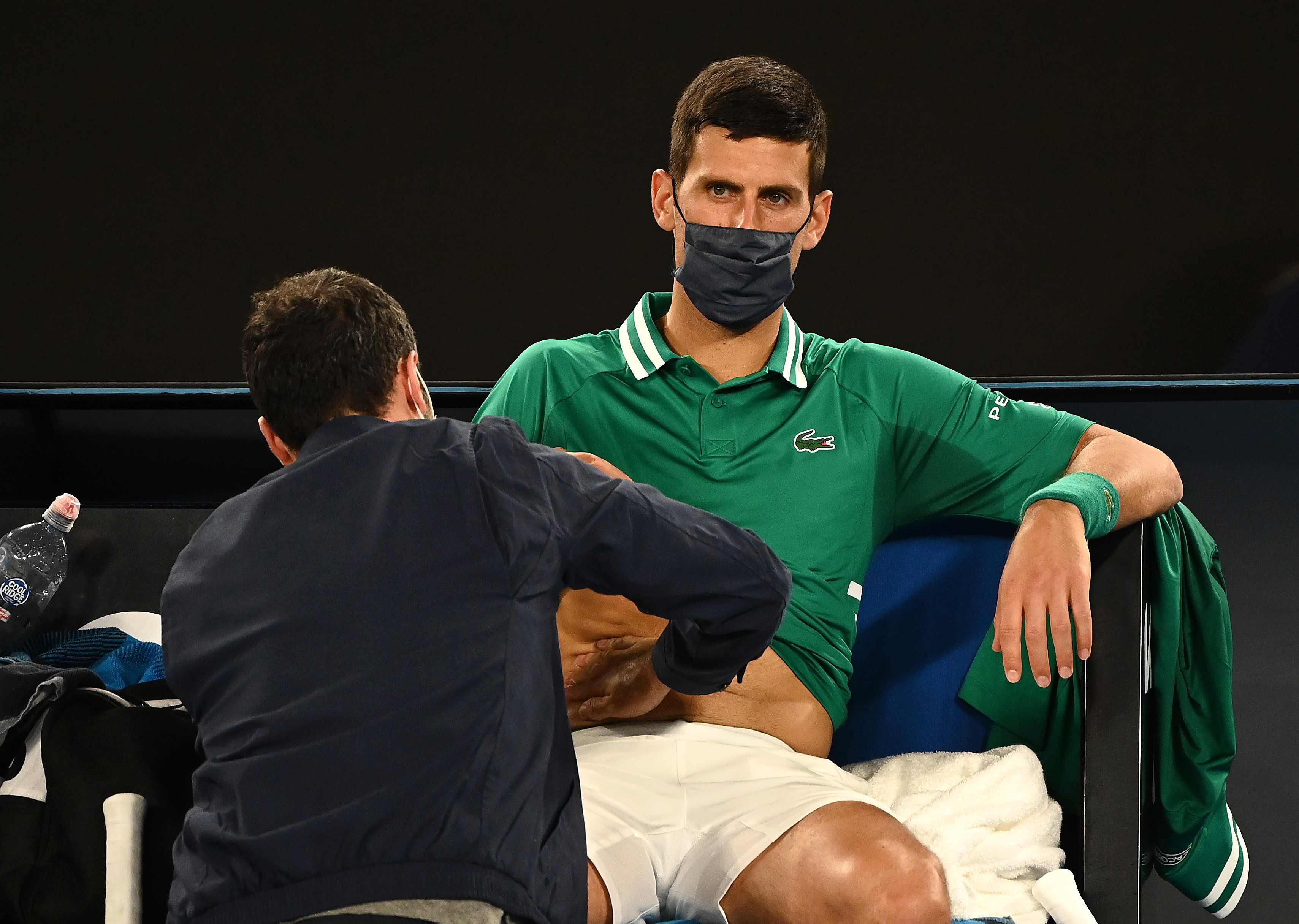 Novak Djokovic es tratado de sus problemas físicos durante el partido ante Taylor Fritz del Open de Australia 2021