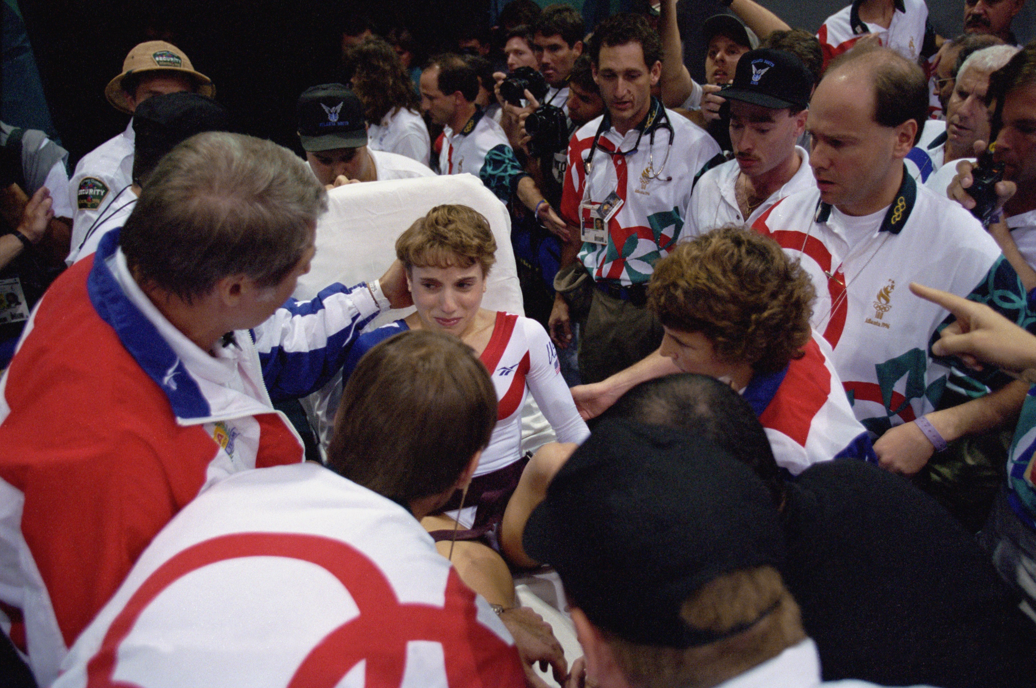 Bela Karolyi and the training staff of the United States attend to Kerri Strug as she cries on a stretcher after injuring herself on her first attempt while competing in the vault