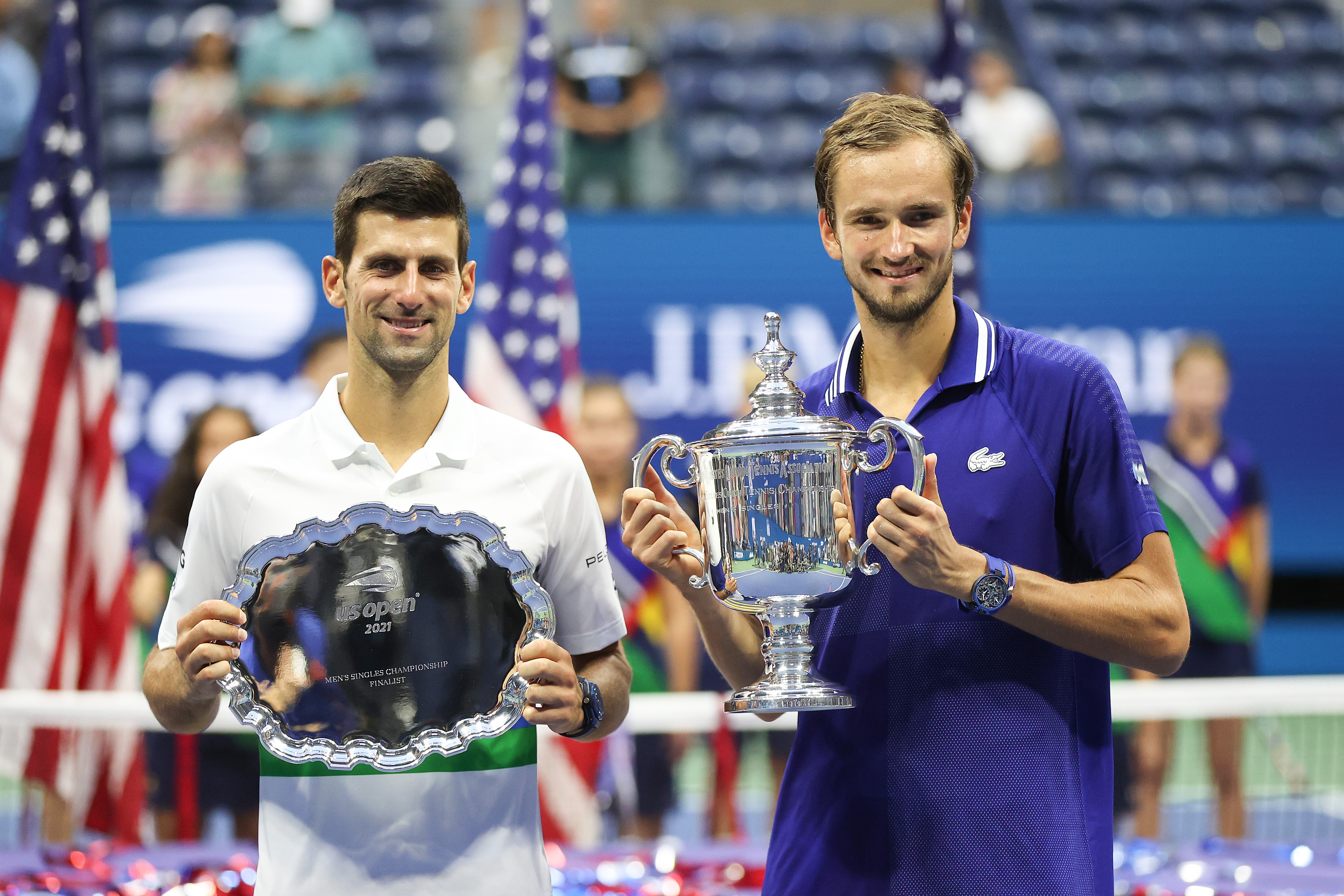 (L-R) Novak Djokovic of Serbia holds the runner-up trophy alongside Daniil Medvedev of Russia who celebrates with the championship trophy after winning their Men's Singles final match on Day Fourteen of the 2021 US Open