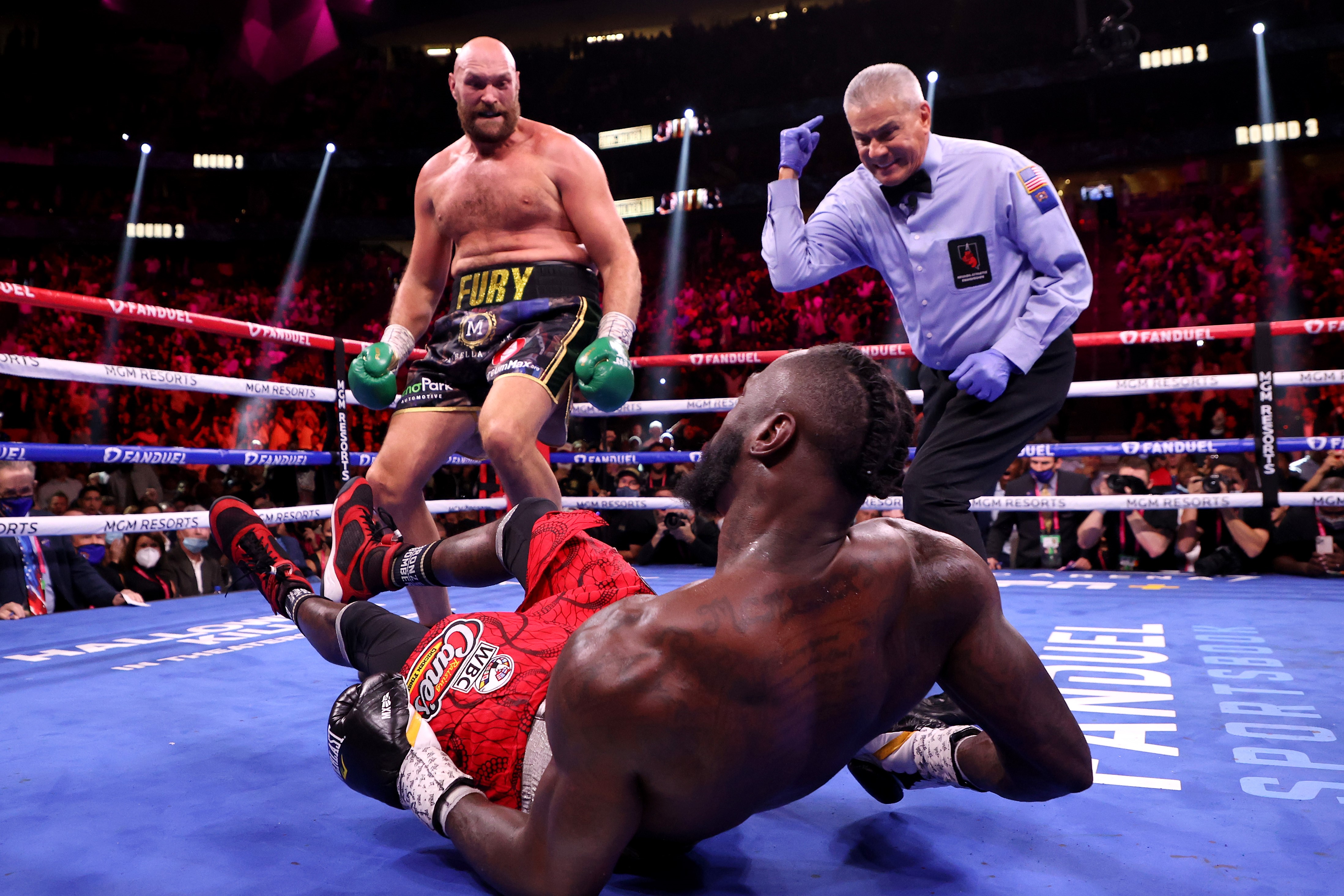 LAS VEGAS, NEVADA - OCTOBER 09: Tyson Fury (top) reacts after knocking down Deontay Wilder in the third round of their WBC Heavyweight Championship title fight at T-Mobile Arena on October 09, 2021 in Las Vegas, Nevada.