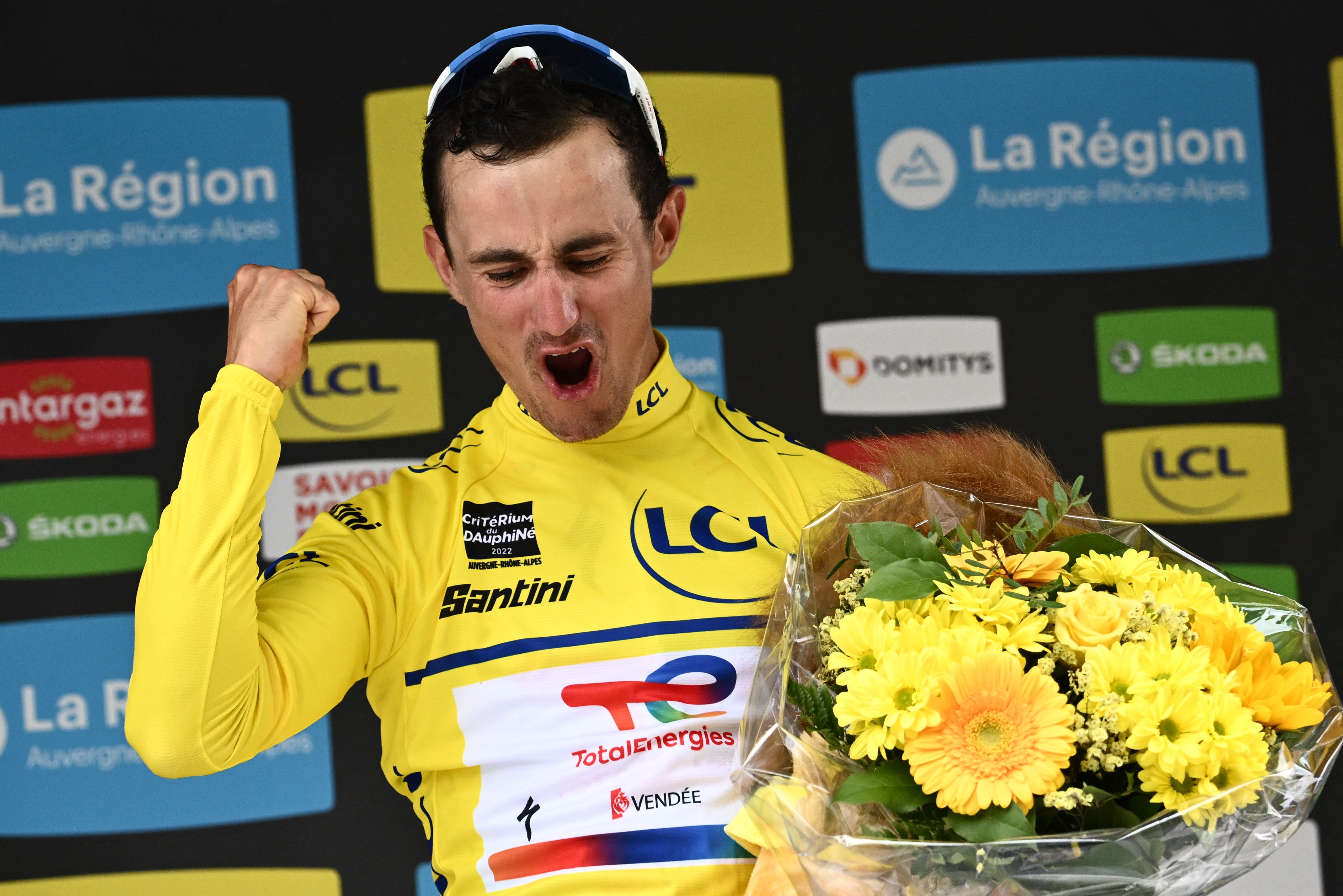 Totalenergies team's French rider Alexis Vuillermoz (C) celebrates with the yellow jersey of the overall leader during the podium ceremony for the second stage of the 74th edition of the Criterium du Dauphine cycling race in Brives-Charensac on June 6, 20